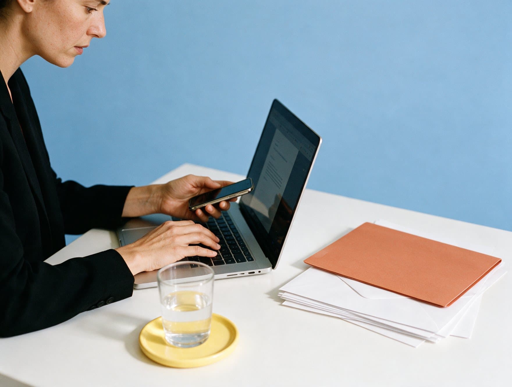 Personne consultant son téléphone devant un ordinateur portable