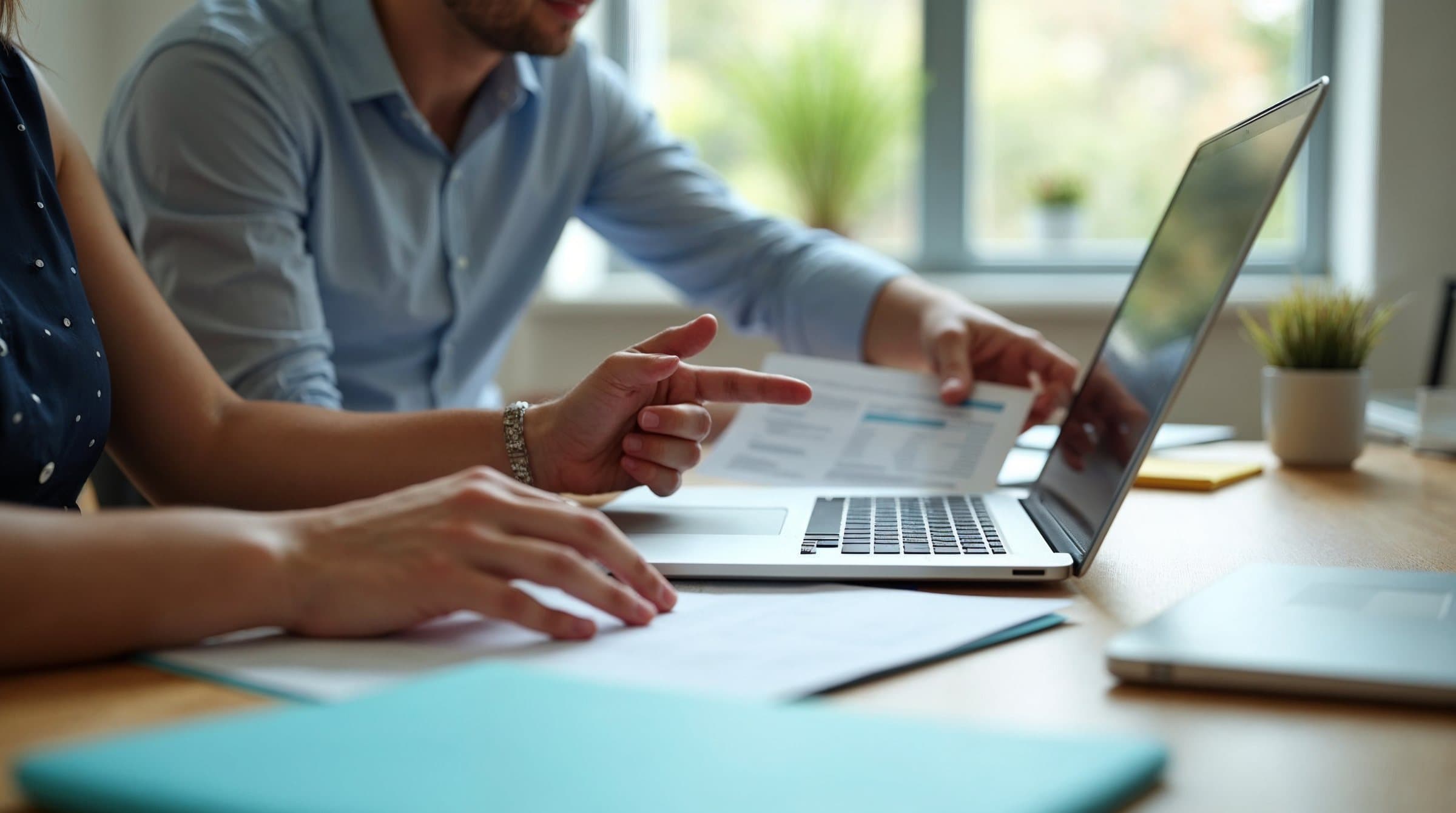 Deux personnes comparant un document imprimé et un ordinateur portable